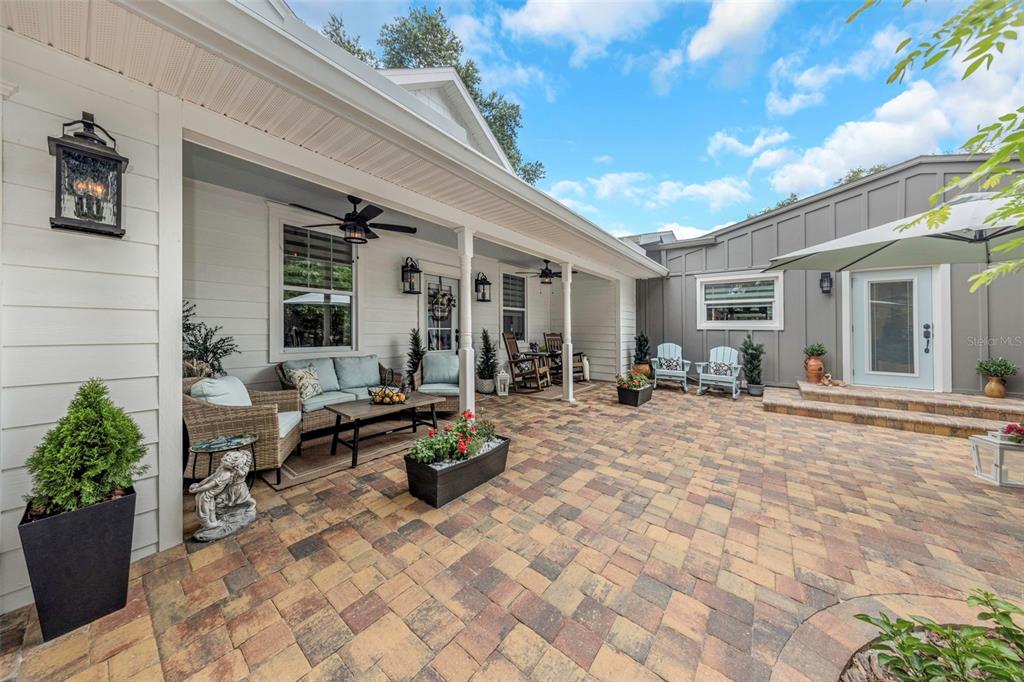 A single-story house with a white brick facade, a covered porch, and a paved walkway — 411 ROEBLING ROAD S, BELLEAIR, FL
