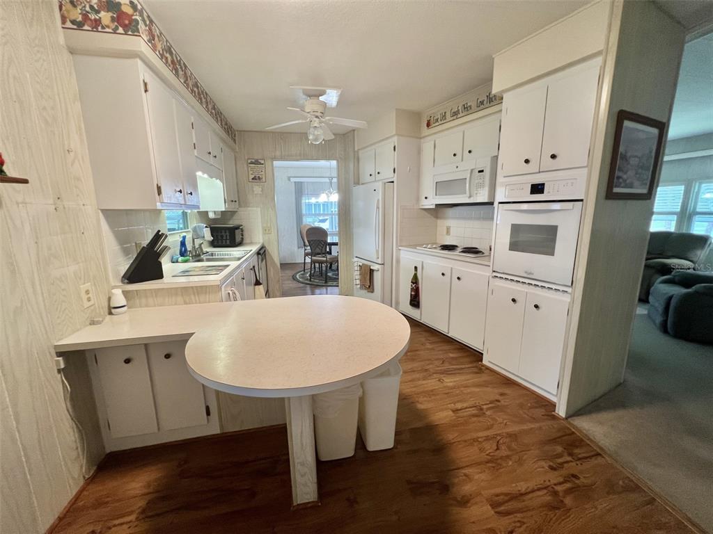 A kitchen features white cabinetry, a round breakfast bar, and wood-look flooring — 424 HAWTHORNE BOULEVARD, LEESBURG, FL