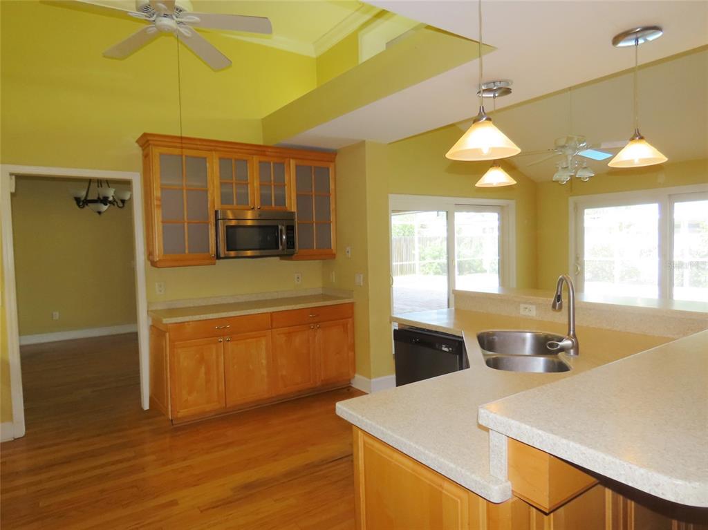 A kitchen with light wood cabinets, a microwave, a sink island, and yellow walls — 7555 PINE VALLEY LANE, SEMINOLE, FL