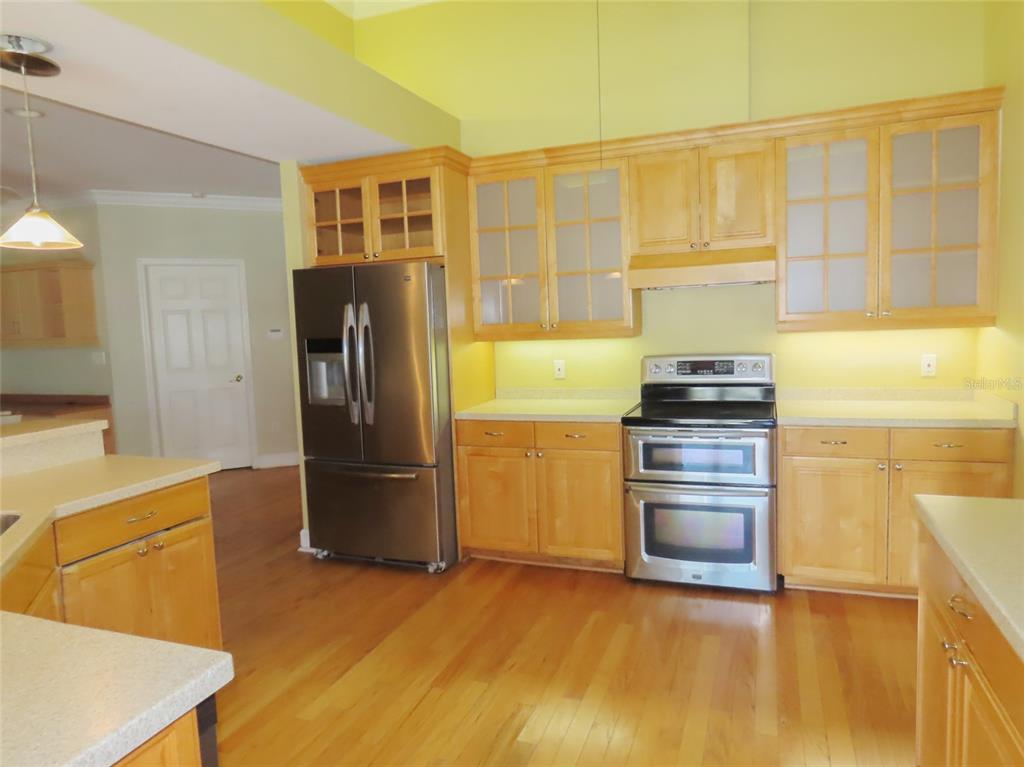 A kitchen features light wood cabinets, stainless steel appliances, and hardwood flooring — 7555 PINE VALLEY LANE, SEMINOLE, FL