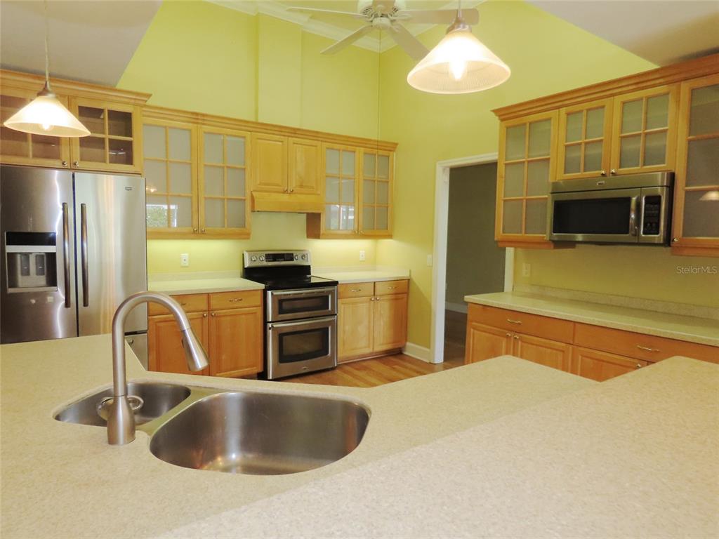 A kitchen features light wood cabinets, stainless steel appliances, and a large island with sink — 7555 PINE VALLEY LANE, SEMINOLE, FL