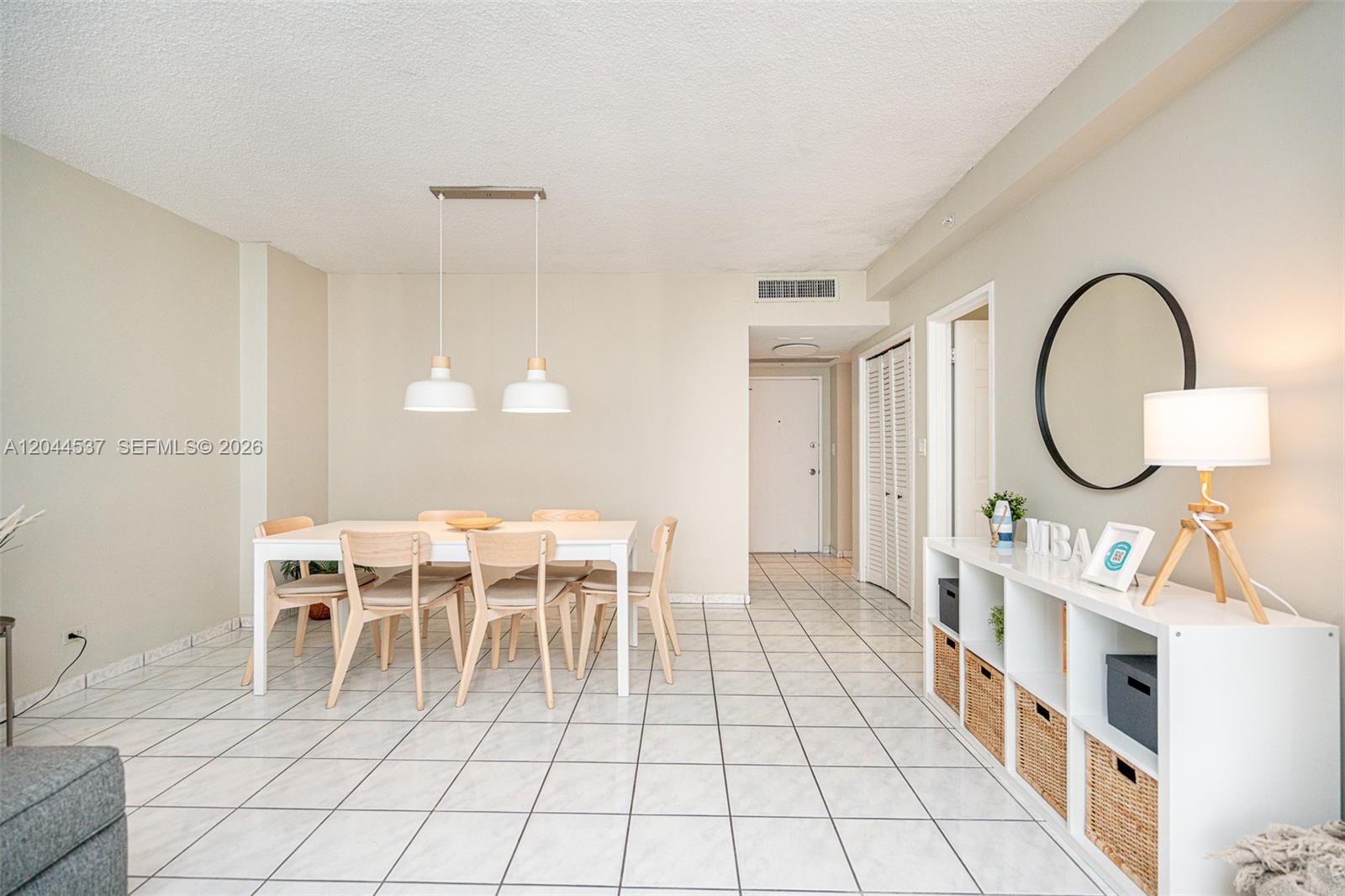 A dining area with a white table, six wooden chairs, and a white storage unit — 5601 Collins Ave # 1517, Miami Beach FL 33140, MIAMI BEACH, FL