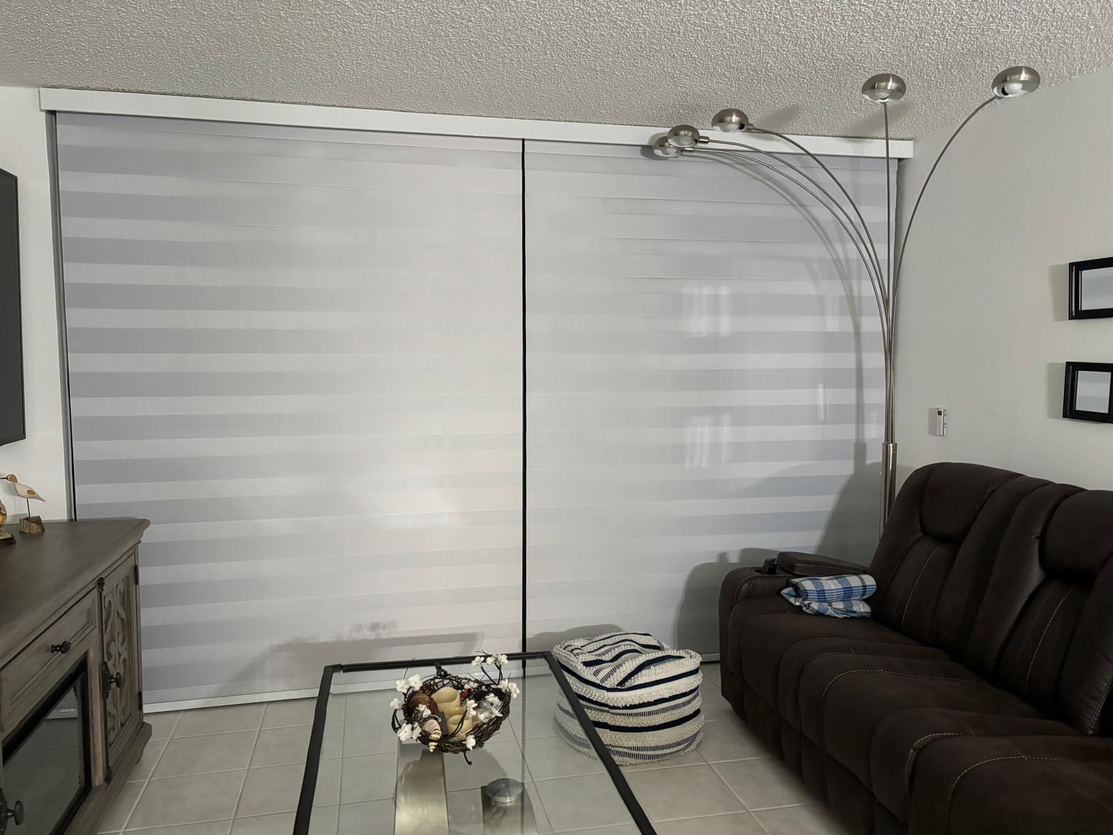 A living room features large striped window shades, a brown sofa, and a floor lamp — 9900 S Ocean Drive # 1, Jensen Beach FL 34957, JENSEN BEACH, FL