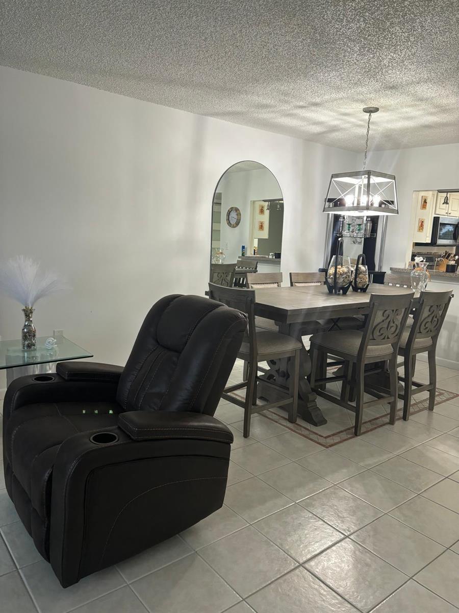A dining area with a wooden table and chairs sits near a brown leather recliner — 9900 S Ocean Drive # 1, Jensen Beach FL 34957, JENSEN BEACH, FL