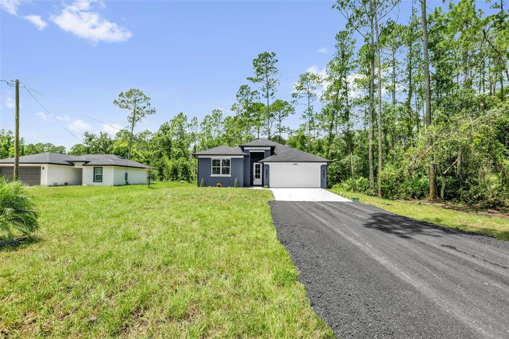 A modern dark gray house with a white garage sits on a grassy lot — 2380 CENTRAL PARKWAY, DELAND, FL