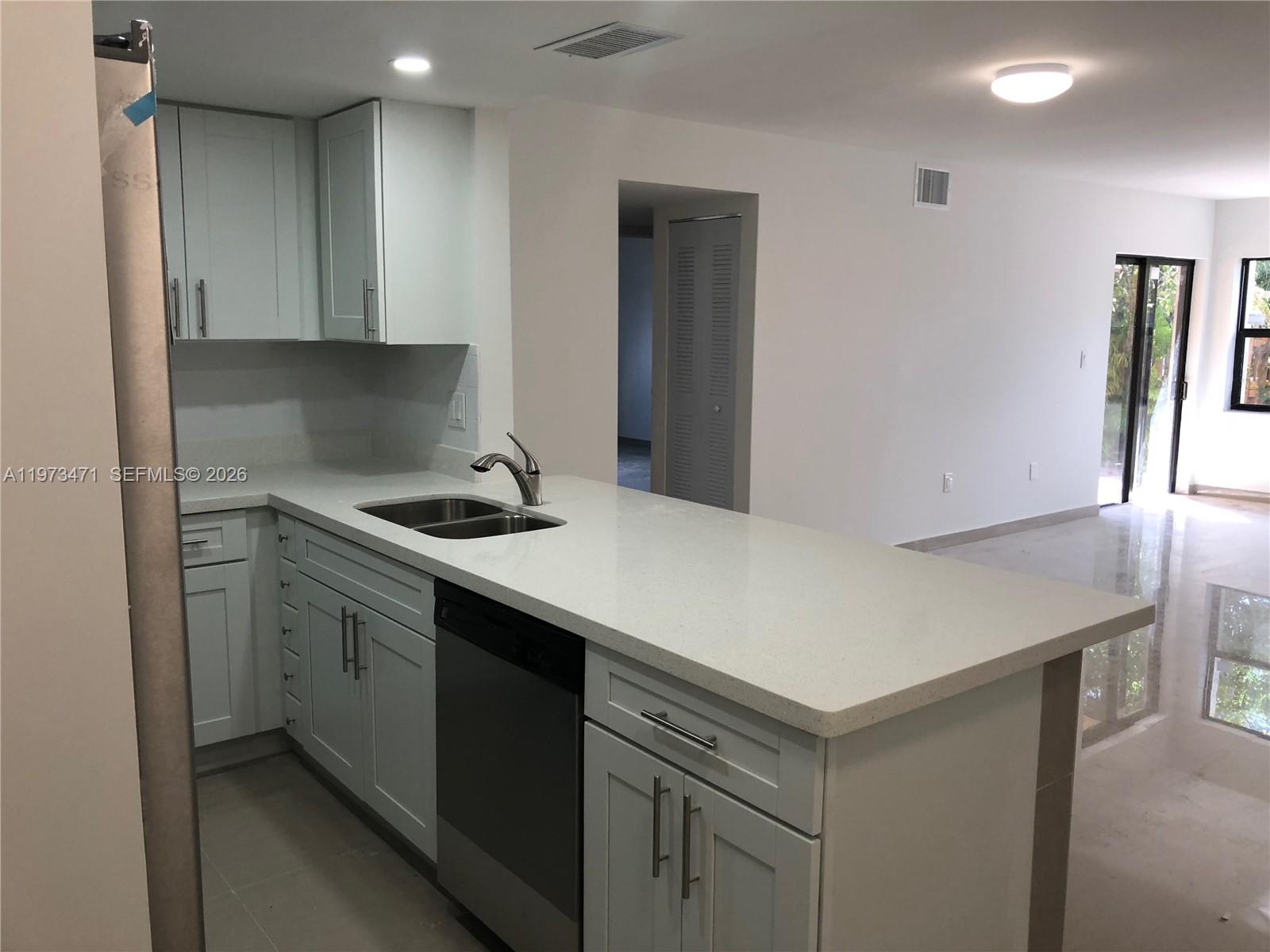 A kitchen features light gray cabinets, white countertops, a stainless steel dishwasher, and tile flooring — 8883 Fontainebleau Blvd # A, Miami FL 33172, MIAMI, FL