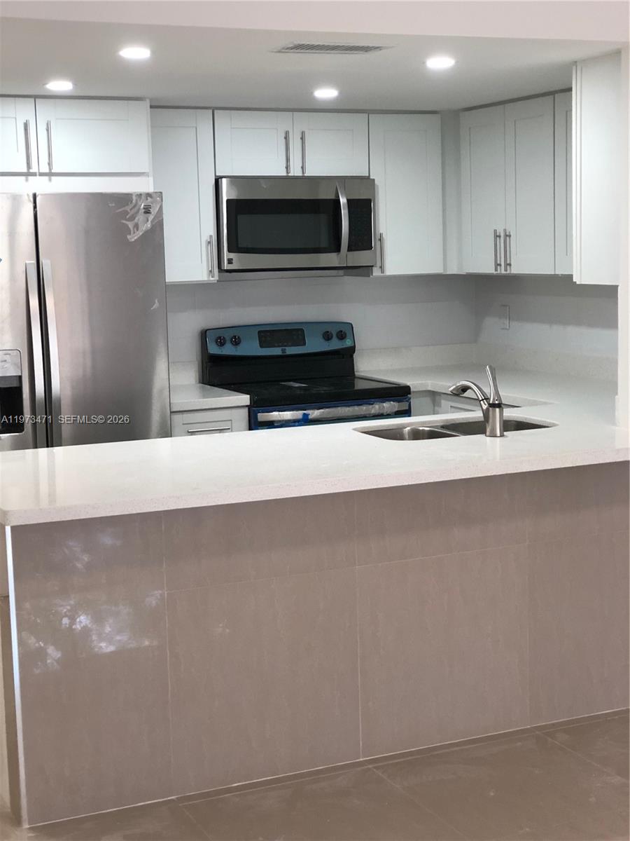 A kitchen features white cabinets, stainless steel appliances, and a light-colored stone countertop — 8883 Fontainebleau Blvd # A, Miami FL 33172, MIAMI, FL