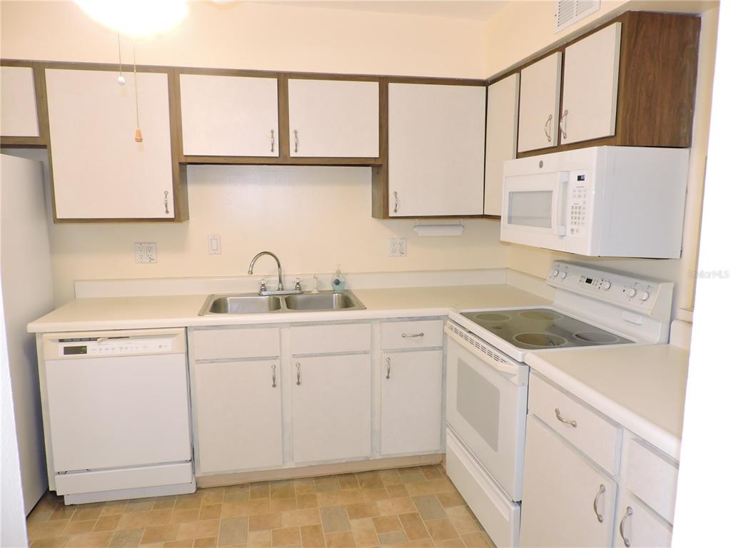 A kitchen features white cabinets, white appliances, a double sink, and light-colored laminate countertops — 130 E JOHNSON AVENUE UNIT 102, LAKE WALES, FL