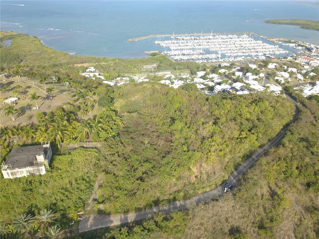 An aerial view shows a hillside lot with vegetation, a road, and a nearby marina — Lot #66 LAS GAVIOTAS CARRETERA 3, CEIBA, FAJARDO 00738 CROSSROAD, FAJARDO, PR