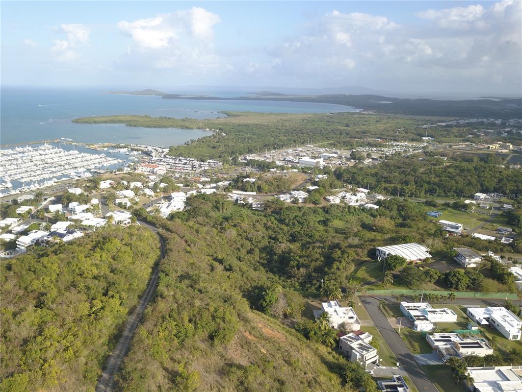 An aerial view shows a coastal landscape with a marina, residential buildings, and lush vegetation — Lot #66 LAS GAVIOTAS CARRETERA 3, CEIBA, FAJARDO 00738 CROSSROAD, FAJARDO, PR