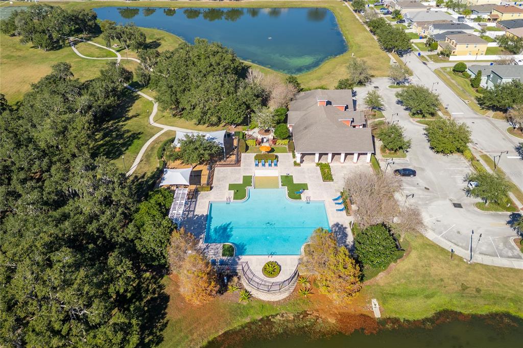 An aerial view of a community swimming pool, clubhouse, and surrounding park with a lake — 5131 QUAKERS PLACE, ST CLOUD, FL
