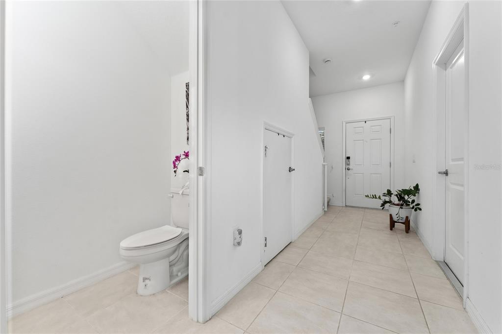 A tiled entryway features a half bathroom, a storage closet, and a white front door — 5131 QUAKERS PLACE, ST CLOUD, FL