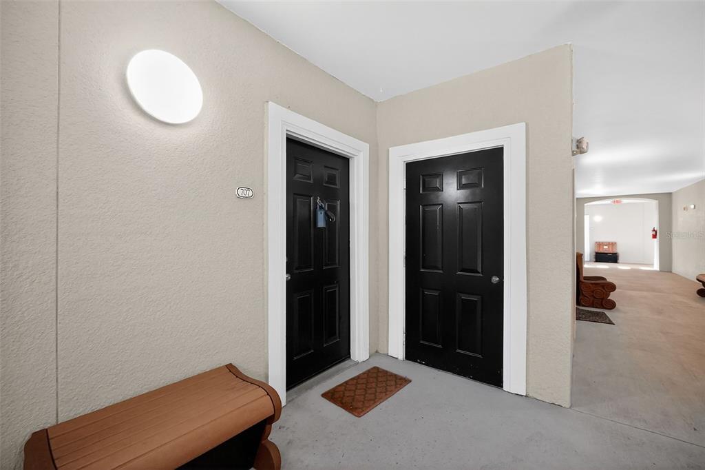 Two black apartment doors are situated in a hallway with a wall-mounted light fixture — 8290 W GATE PARKWAY UNIT 707, JACKSONVILLE, FL