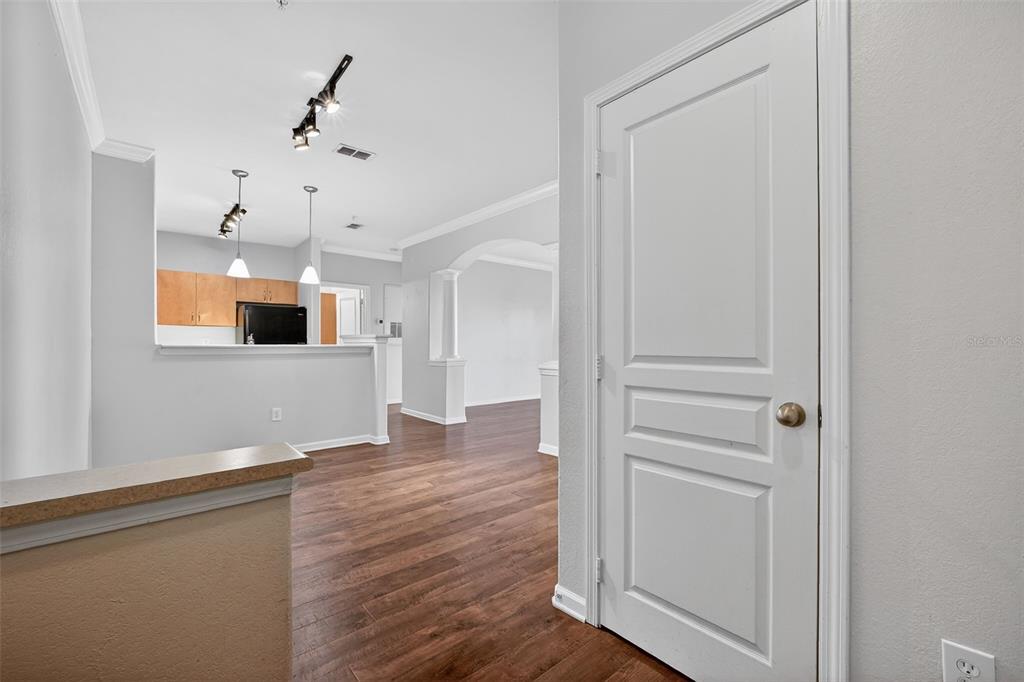 A view of a hallway with wood-look flooring leading to a kitchen with light-colored cabinets — 8290 W GATE PARKWAY UNIT 707, JACKSONVILLE, FL