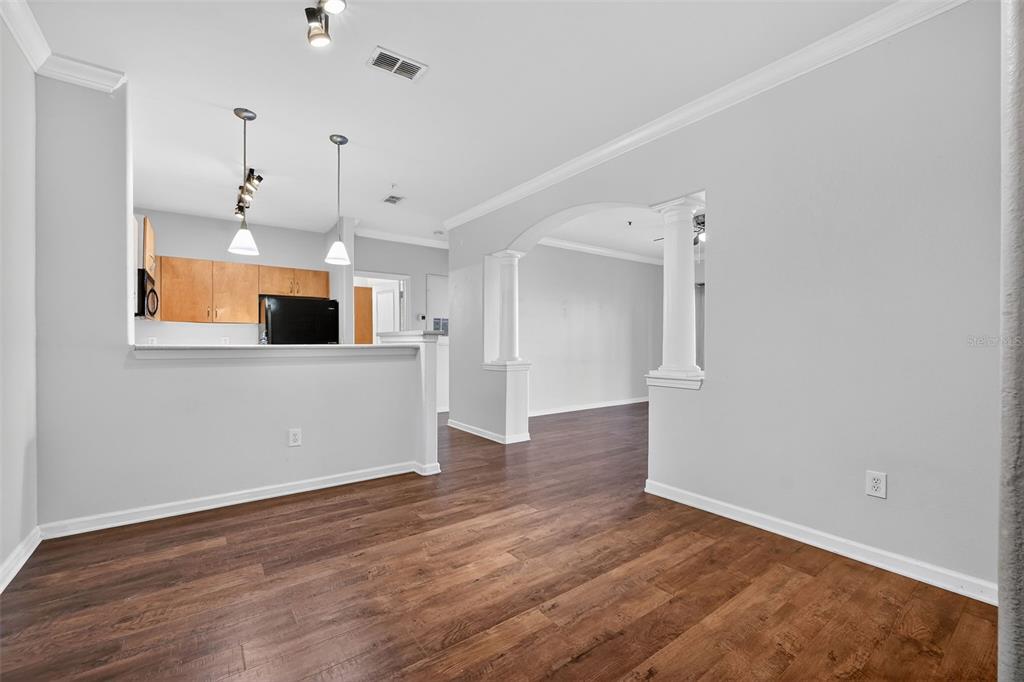 An interior view shows a dining area with wood-look flooring, an arched entryway, and kitchen — 8290 W GATE PARKWAY UNIT 707, JACKSONVILLE, FL