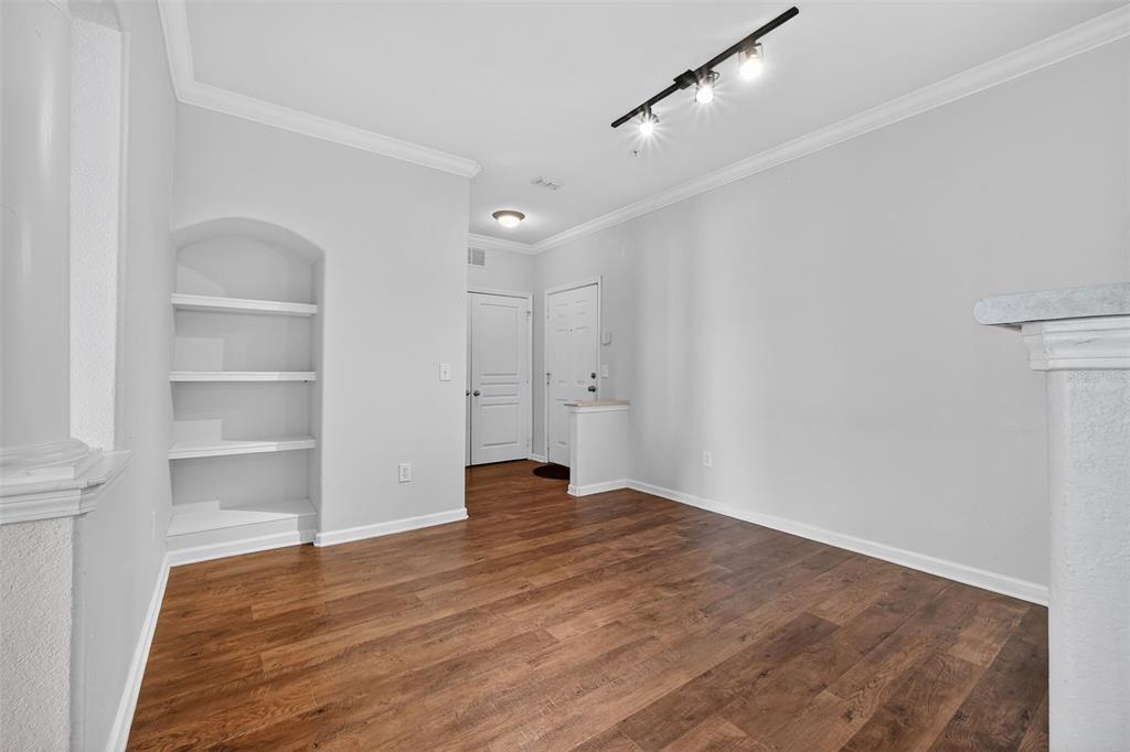 An empty room with wood-look flooring, white walls, a built-in arched shelf, and track lighting — 8290 W GATE PARKWAY UNIT 707, JACKSONVILLE, FL