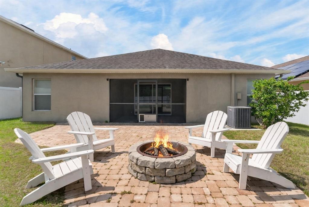 A backyard features a paver patio with a fire pit and a white vinyl fence — 13214 ROYAL PINES AVENUE, RIVERVIEW, FL