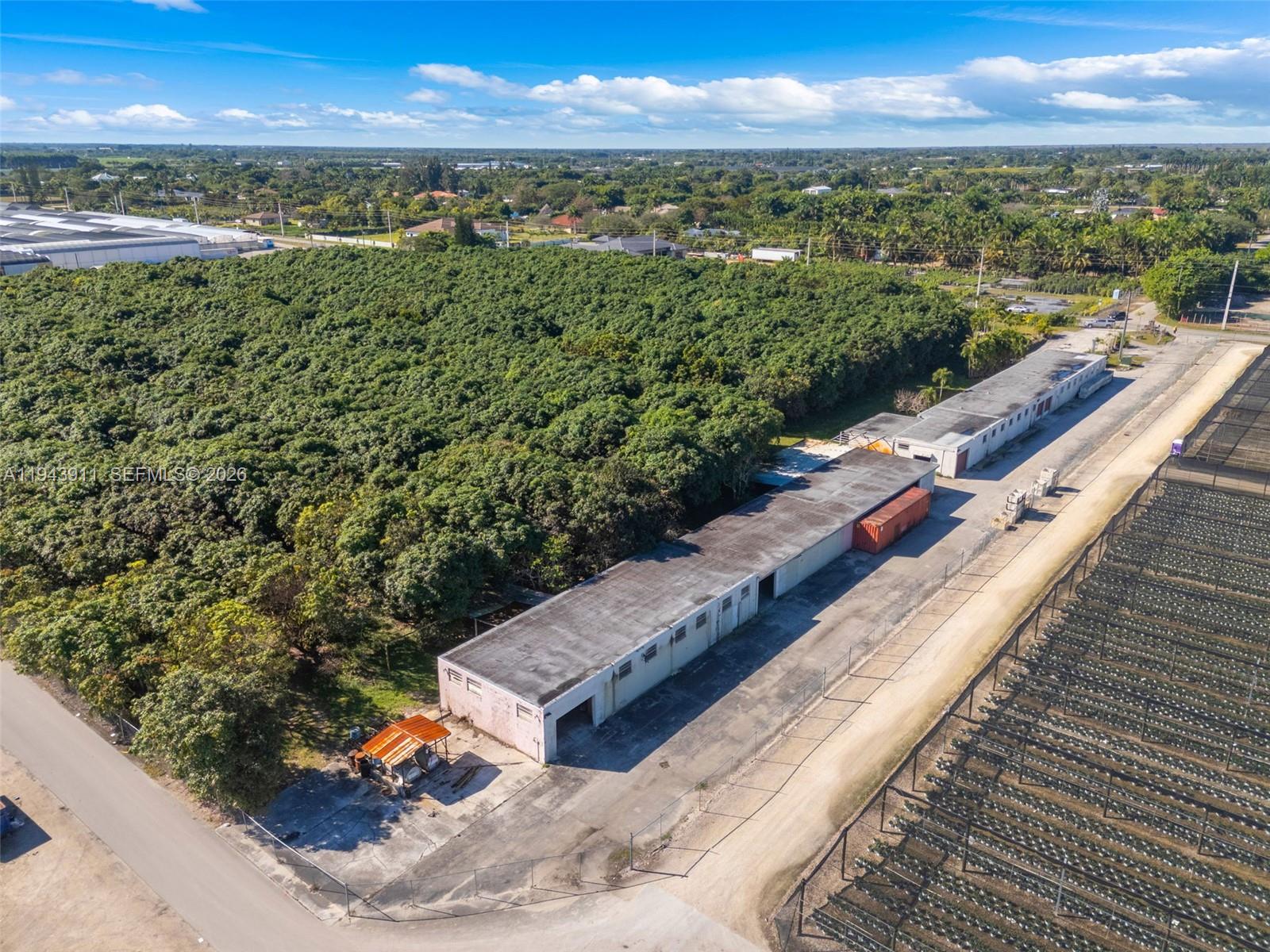 A paved road leads toward a gated entrance lined with palm trees and stone borders — 20601 SW 194th Ave, Miami FL 33187, MIAMI, FL