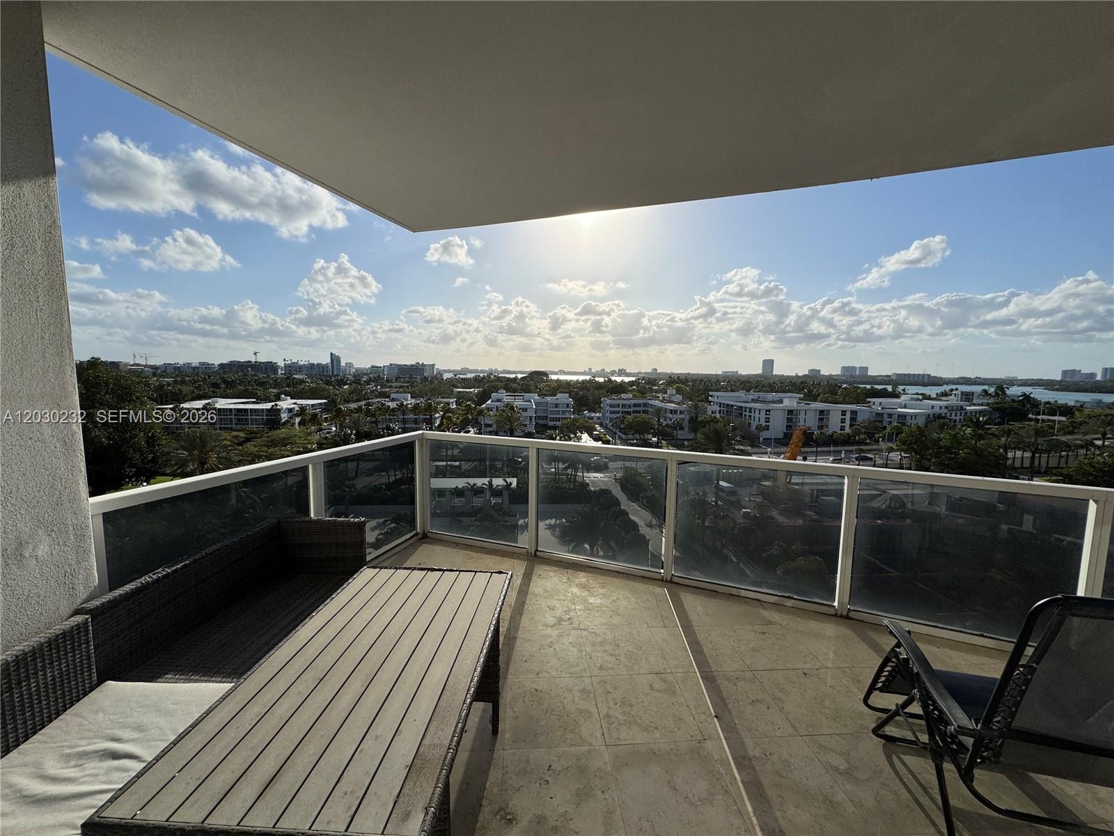 A balcony with a glass railing overlooks a city skyline and water under a sunny sky — 10225 Collins Ave # 503, Bal Harbour FL 33154, BAL HARBOUR, FL