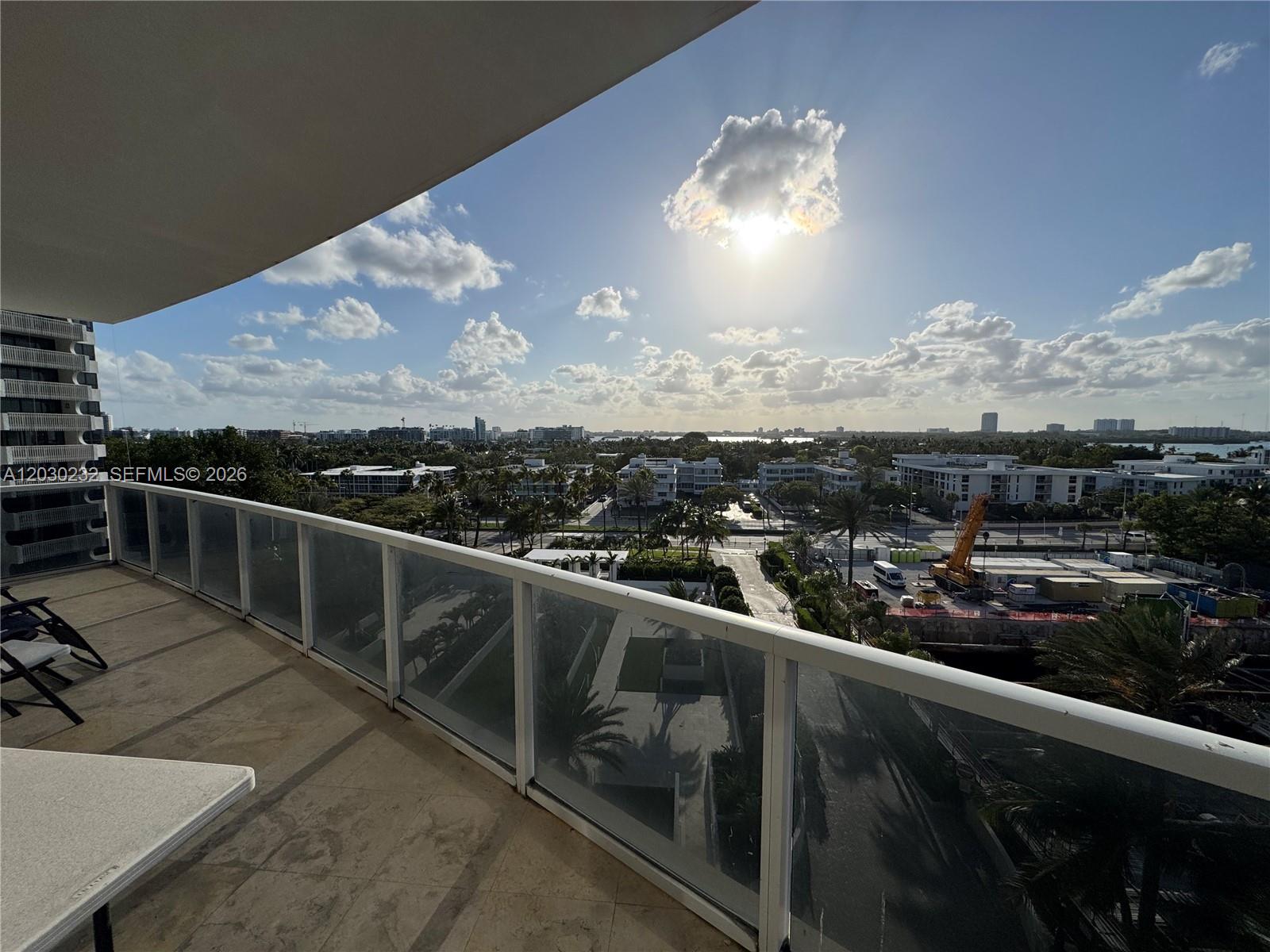 A balcony with a glass railing overlooks a city landscape with a construction site — 10225 Collins Ave # 503, Bal Harbour FL 33154, BAL HARBOUR, FL