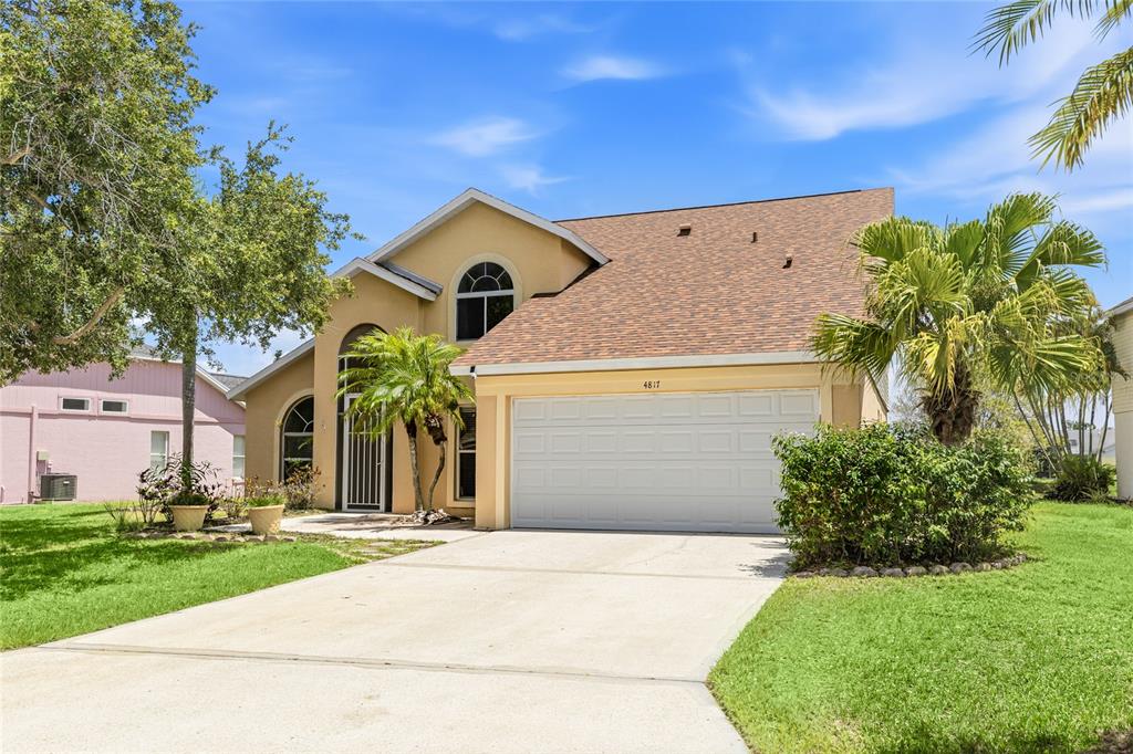 A two-story house with a tan stucco exterior, a two-car garage, and a palm tree — 4817 11TH AVENUE CIRCLE E, BRADENTON, FL