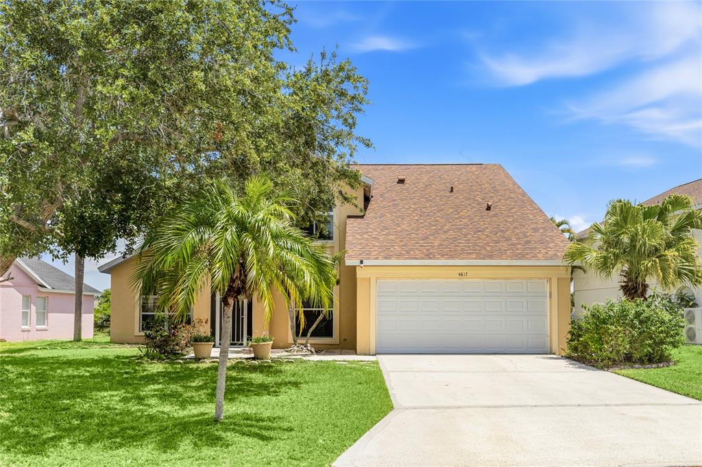 A two-story house with a tan exterior, a two-car garage, and a palm tree — 4817 11TH AVENUE CIRCLE E, BRADENTON, FL