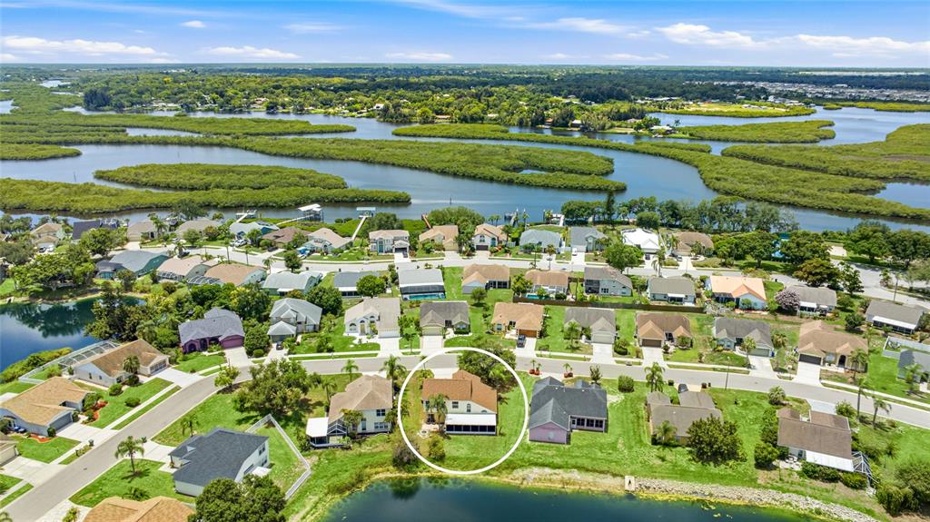 An aerial view shows a suburban neighborhood with a circled house near a small lake — 4817 11TH AVENUE CIRCLE E, BRADENTON, FL