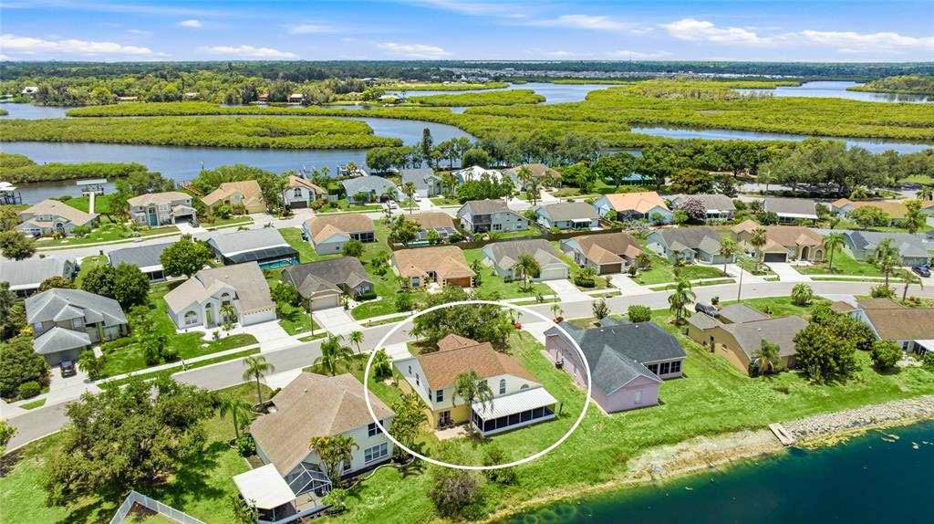 An aerial view shows a suburban house with a screened-in patio near a waterfront — 4817 11TH AVENUE CIRCLE E, BRADENTON, FL