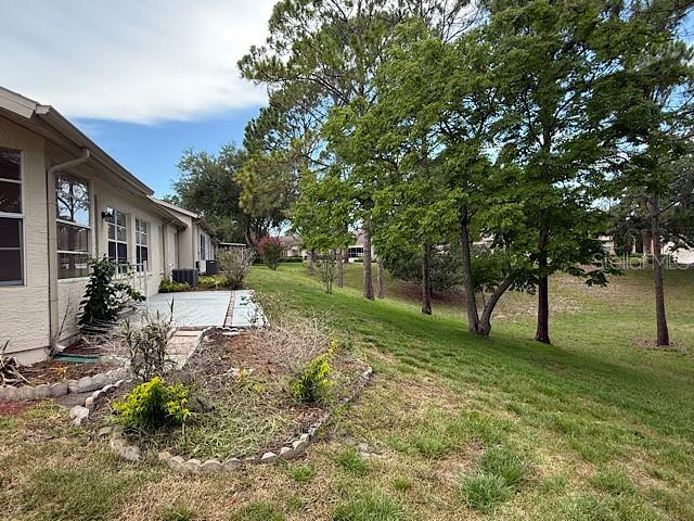 A view of the side of a house with a patio and a grassy yard — 2232 SPRINGMEADOW DRIVE, SPRING HILL, FL