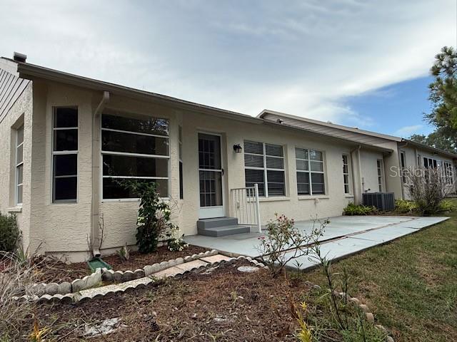 The exterior of a beige house features a concrete patio, large windows, and a door — 2232 SPRINGMEADOW DRIVE, SPRING HILL, FL