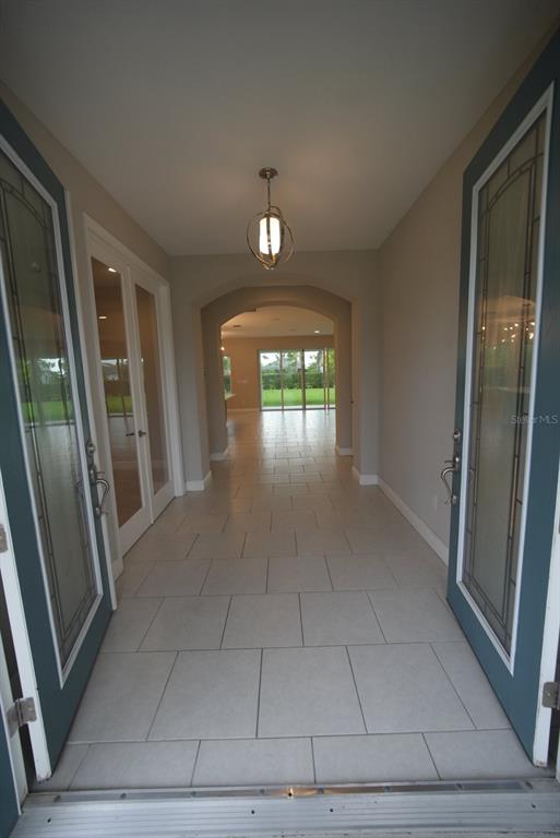 A tiled entryway leads through an arched hallway toward a bright, open living space — 5450 WAYFARER AVENUE, APOLLO BEACH, FL