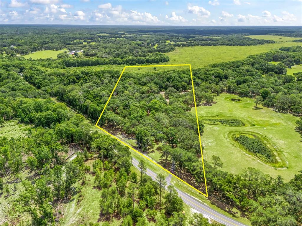 An aerial view shows a wooded lot outlined in yellow next to a paved road — 4801 COUNTY ROAD 575, BUSHNELL, FL