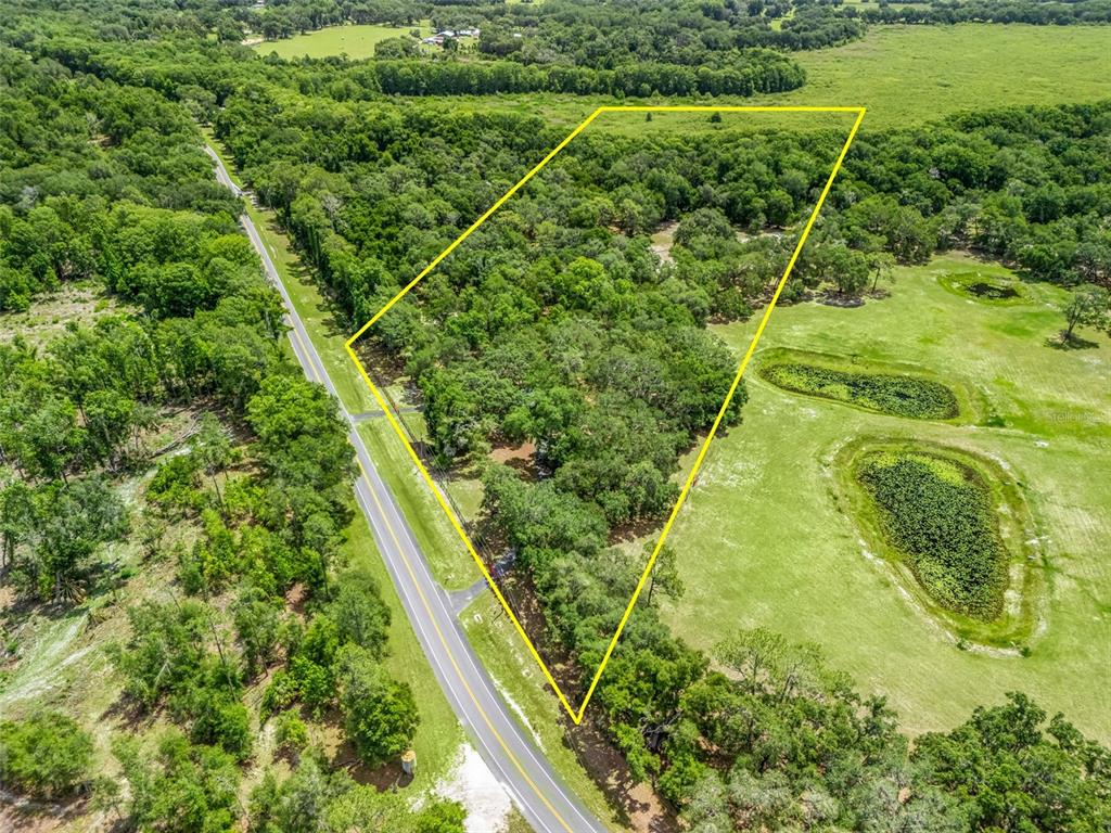 An aerial view shows a triangular plot of wooded land bordering a paved road — 4801 COUNTY ROAD 575, BUSHNELL, FL