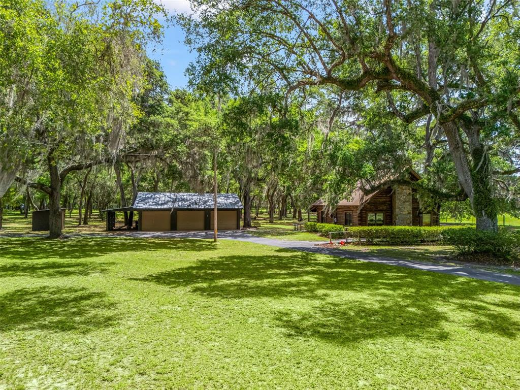A log cabin and a detached three-car garage sit on a grassy lot with trees — 4801 COUNTY ROAD 575, BUSHNELL, FL