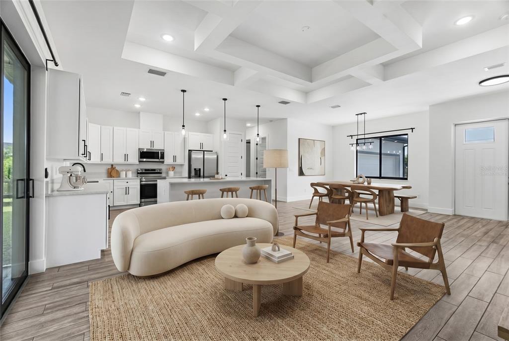 An open-concept living room and kitchen featuring white cabinetry, a curved sofa, and wood flooring — 9487 ROSEBUD CIRCLE, PORT CHARLOTTE, FL