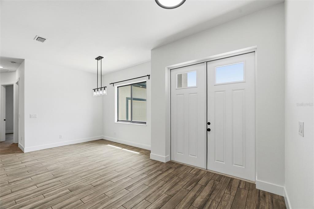 A dining area features wood-look tile flooring, a modern light fixture, and double entry doors — 9487 ROSEBUD CIRCLE, PORT CHARLOTTE, FL
