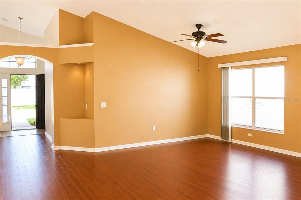 An empty living room with hardwood floors, a vaulted ceiling, and a ceiling fan — 145 THORNBURY DRIVE, KISSIMMEE, FL