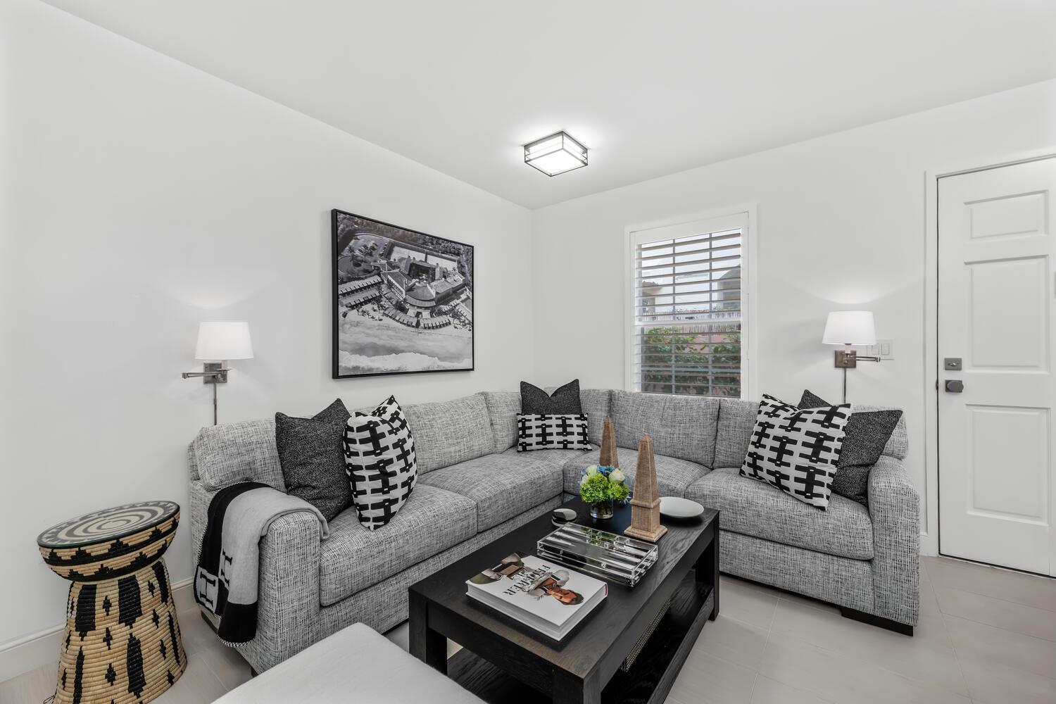 A living room features a gray sectional sofa, a black coffee table, and wall-mounted lamps — 134 Peruvian Avenue # 104, Palm Beach FL 33480, PALM BEACH, FL