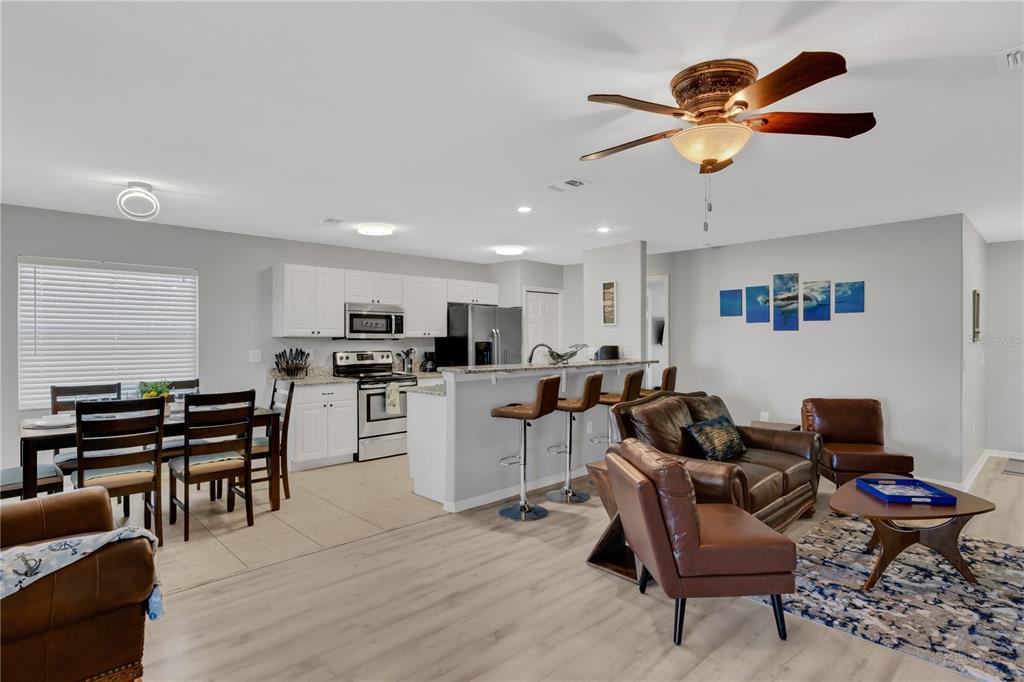 An open-concept living room and kitchen featuring light wood floors, white cabinets, and leather furniture — 2757 FEIFFER CIRCLE, SARASOTA, FL