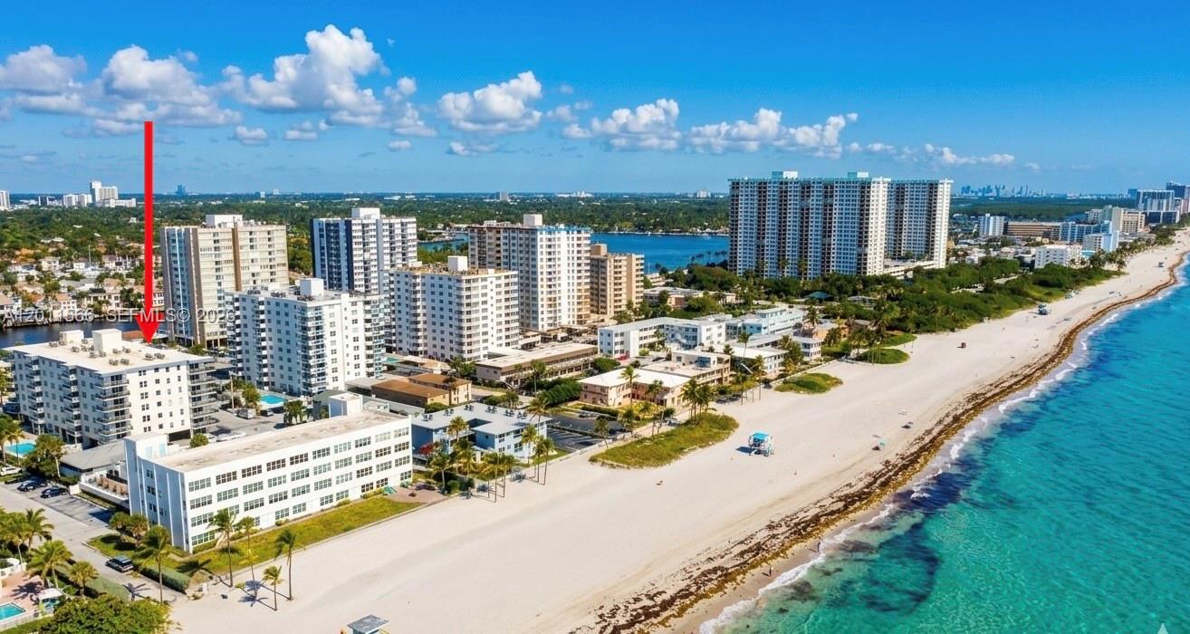 An aerial view shows a coastal beach with multiple high-rise apartment buildings and palm trees — 1801 S Ocean Dr # 203, Hollywood FL 33019, HOLLYWOOD, FL