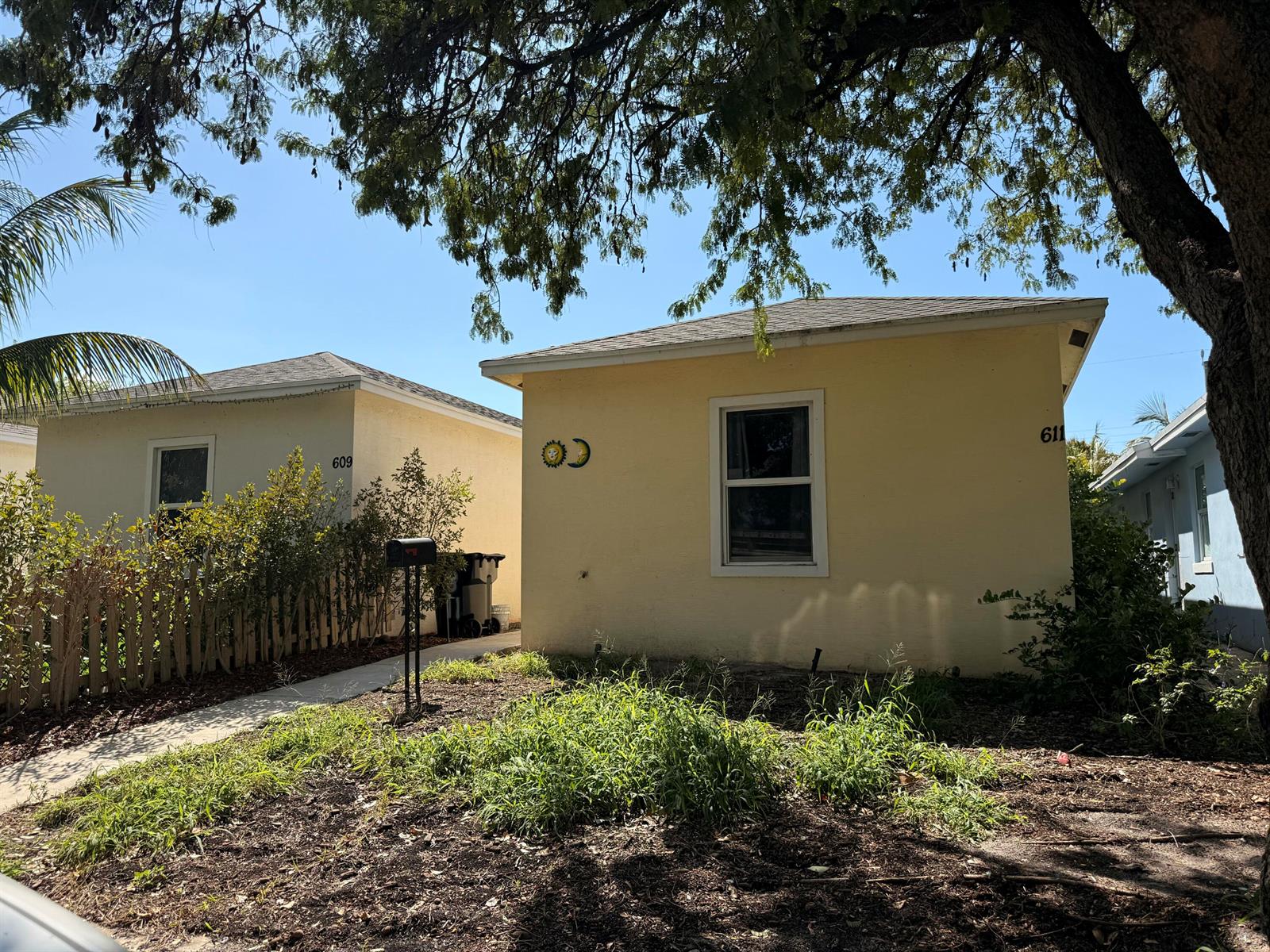 Two small, yellow, single-story houses stand side-by-side under a large tree on a sunny day — 611 N F Street, FL 33460, FL