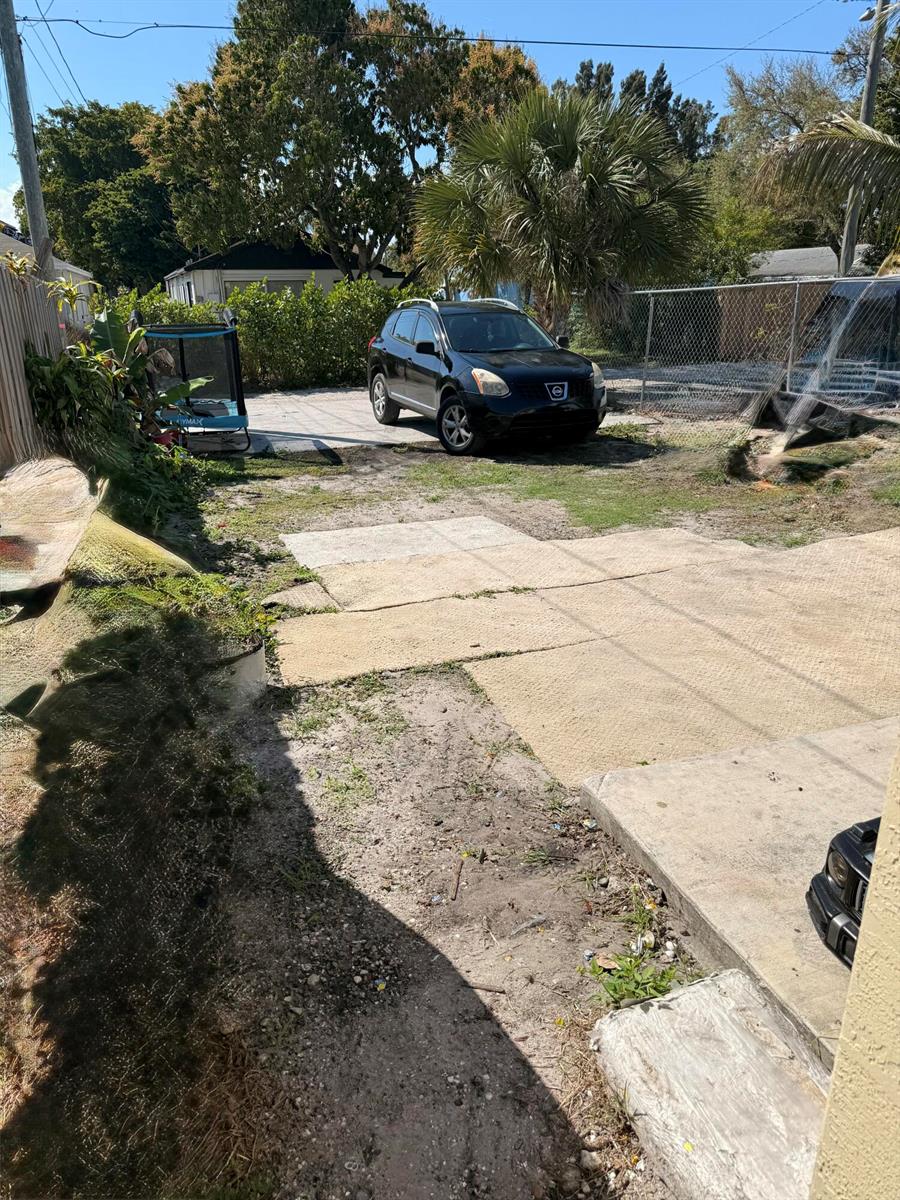 A black SUV is parked on a gravel and concrete driveway in a residential yard — 611 N F Street, FL 33460, FL