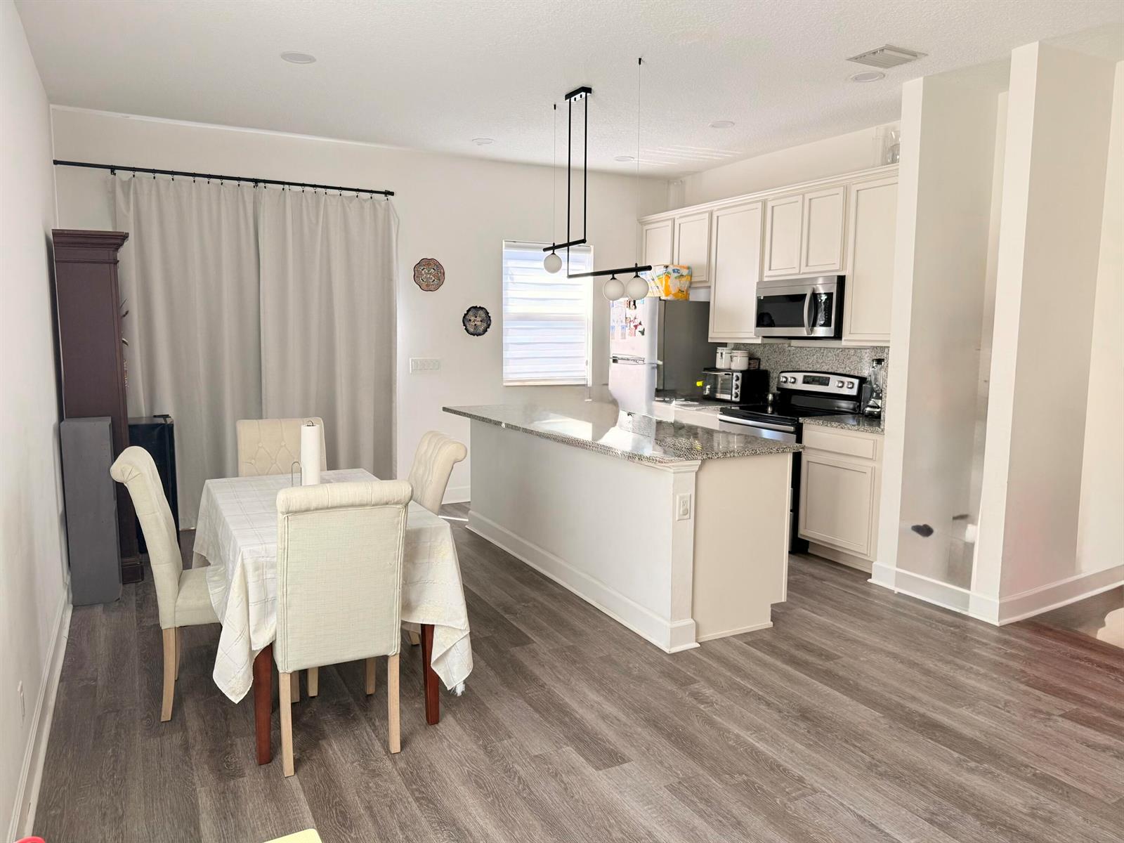 An open-concept kitchen and dining area features white cabinetry, granite countertops, and wood-look flooring — 611 N F Street, FL 33460, FL