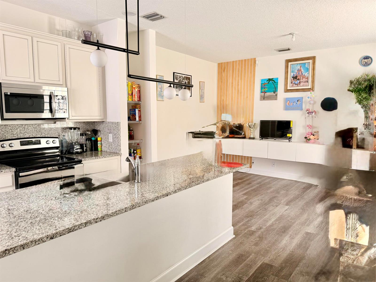 A kitchen with granite countertops and white cabinets opens into a living area with wood flooring — 611 N F Street, FL 33460, FL