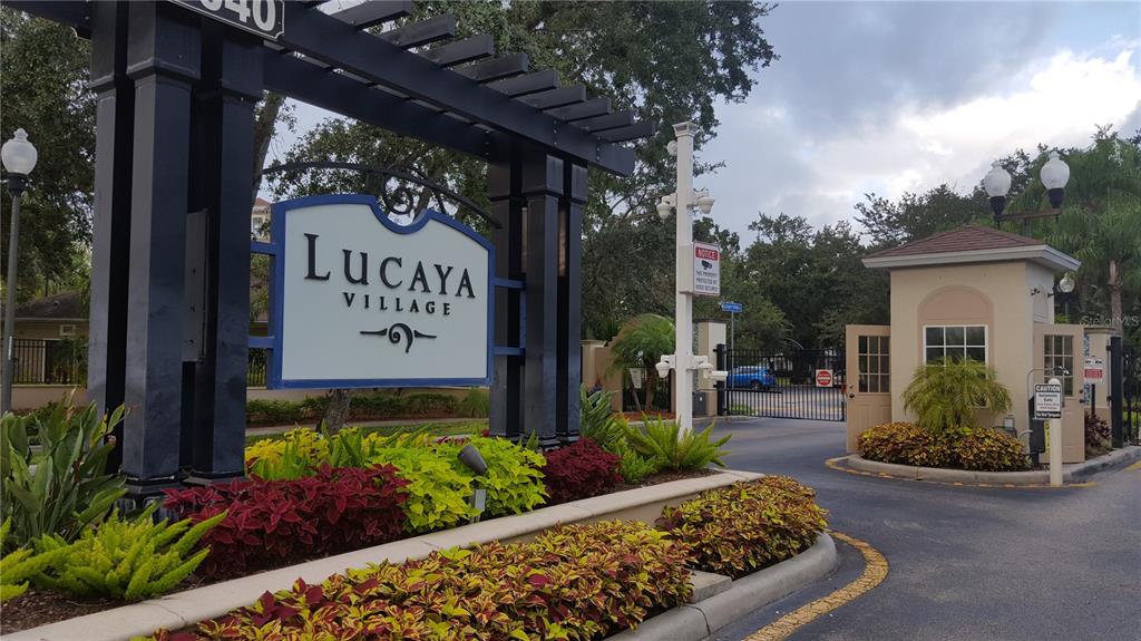 The entrance to Lucaya Village features a gated community sign, landscaping, and a guard house — 5362 DIPLOMAT COURT UNIT 108, KISSIMMEE, FL