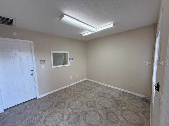 An empty room features beige walls, a white door, and patterned tile flooring — 15 UTILITY DRIVE UNIT C, PALM COAST, FL