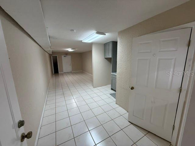 A long room features white tiled floors, a white door, and a small kitchenette area — 15 UTILITY DRIVE UNIT C, PALM COAST, FL