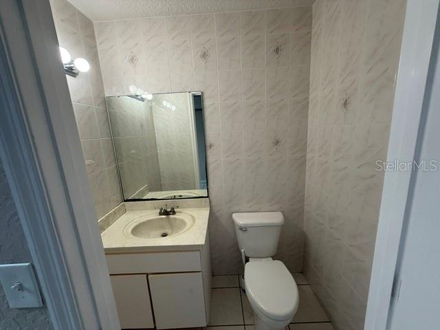 A small bathroom features a white vanity, a wall-mounted mirror, and a white toilet — 15 UTILITY DRIVE UNIT C, PALM COAST, FL