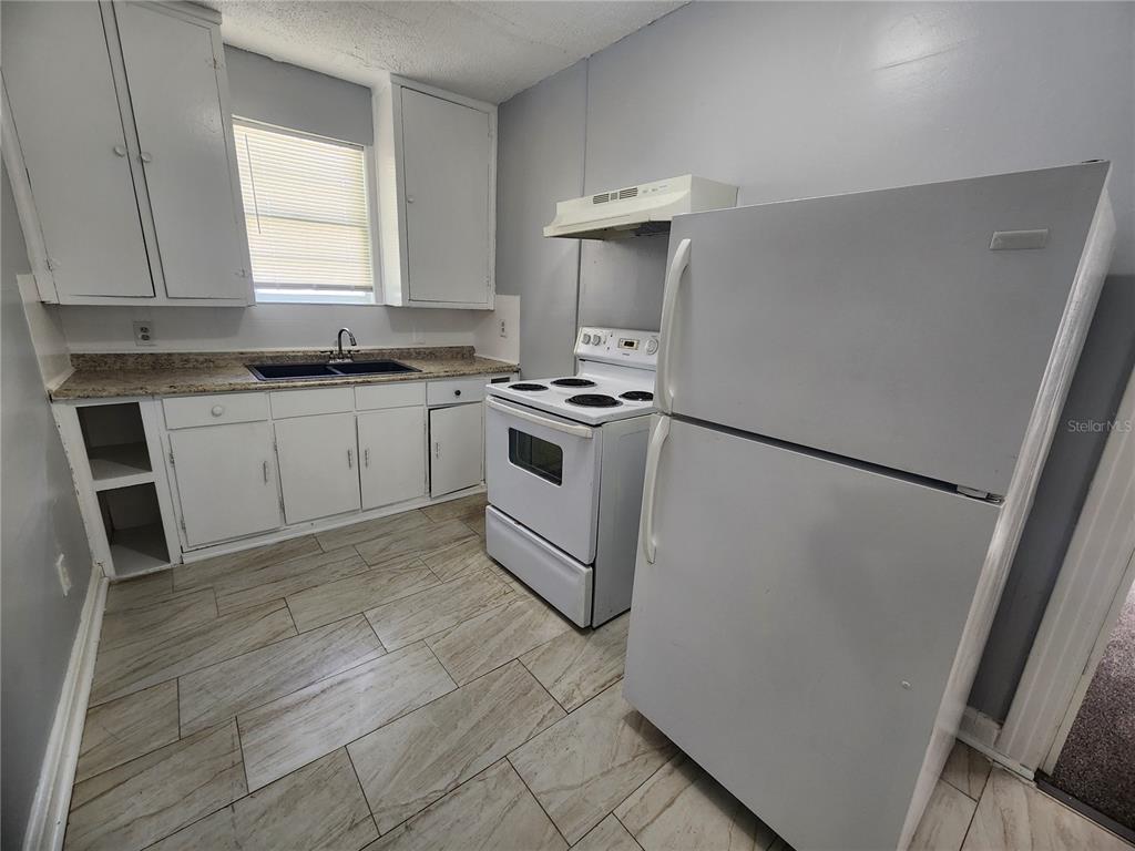 A kitchen features white cabinets, a white stove, a refrigerator, and light-colored tile flooring — 1512 W 31ST STREET, JACKSONVILLE, FL