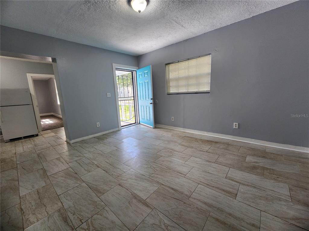 A room with gray walls, tiled flooring, a light blue door, and a white refrigerator — 1512 W 31ST STREET, JACKSONVILLE, FL